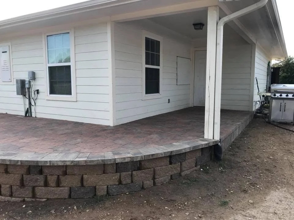 Paver patio with block retaining wall behind a house in College Station, Texas